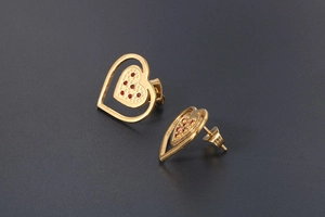 Detailed view of hollow heart stud earrings in 18K gold finish with red cubic zirconia