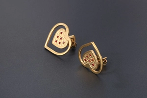 Macro shot of 18K gold plated heart earrings with red crystals and layered metal detail