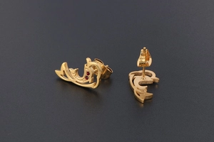 Macro view of 18K gold dolphin earrings with red zircon eyes and butterfly backs