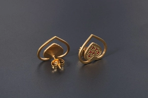 Detail shot of 18K gold plated double heart studs with red gemstone accents and butterfly backs