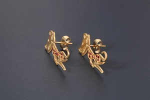 Detailed macro view of gold cat stud earrings with red crystal accents and hollow design