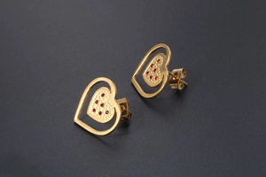 Detailed view of 18K gold heart earrings with red pavé zircons and hollow design