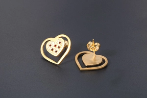 Close-up of gold-plated heart earrings with red gemstones and butterfly backings