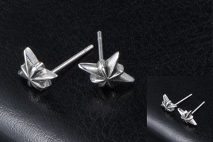 Macro detail of gothic octagram star earrings with oxidized finish on black leather background