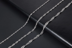 Macro detail of silver water wave chain necklaces showing high precision metal textures