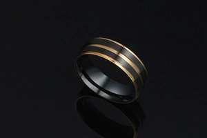 Détail macro d'une bague pour homme en titane noir brossé avec bords dorés et face polie