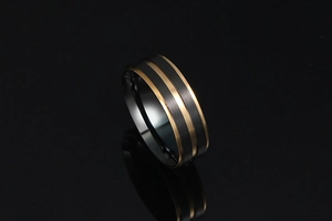 Gros plan détaillé d'une bague en acier titane noir brossé avec doubles rainures dorées et reflet