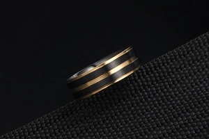 Gros plan détaillé du fini métal brossé noir et de la rainure dorée sur la bague en acier
