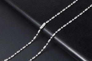 Vue macro d'une chaîne à billes en acier inoxydable argenté sur fond en cuir noir texturé