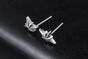 Macro shot of silver octagonal star stud earrings on a premium black leather texture