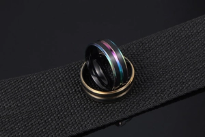 Détail de bagues en acier noir avec rainures centrales colorées et dorées sur ruban noir