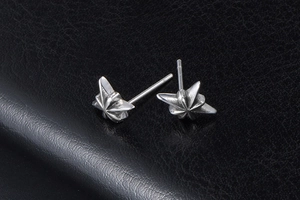 Detail view of retro silver star stud earrings with gothic texture on black leather