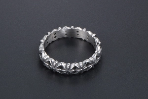 Close-up of vintage silver ring featuring raised floral cross relief and punk style carvings