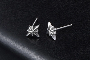 Macro detail of octagonal star stud earrings with vintage oxidized finish on black leather