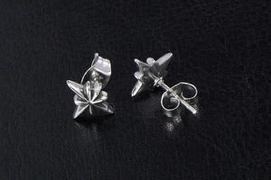 Macro detail of silver octagonal star stud earrings on a black leather texture