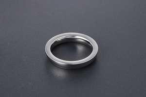 Close-up of a minimalist silver titanium steel ring on a dark textured background