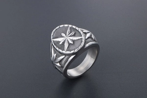 Gros plan sur une bague chevalière vintage argentée avec étoile à huit branches gravée