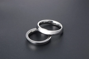 Close-up of minimalist polished silver steel couple rings on dark textured background