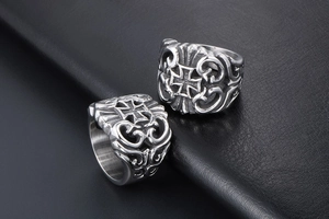 Detail of vintage gothic titanium steel rings with cross patterns on black leather background