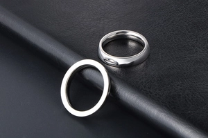 Close-up of polished silver titanium steel minimalist rings on black leather texture
