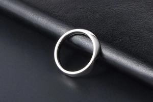 Detailed view of a polished silver titanium steel ring resting on a black leather surface