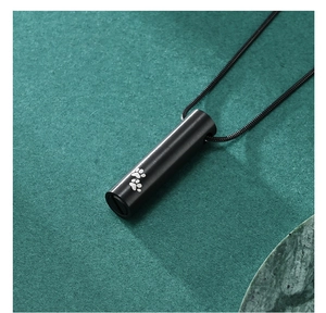 Macro shot of black stainless steel cremation urn pendant with dual white paw print design