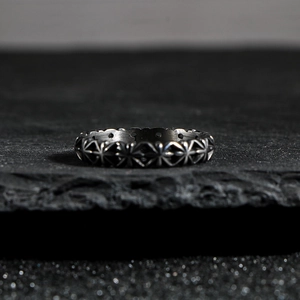 Vintage oxidized silver ring with cross patterns on a textured grey rock background