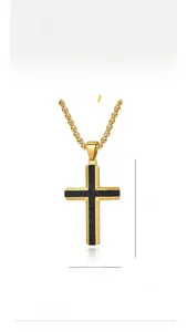 Détail d'un pendentif croix en acier titane doré avec insert en fibre de carbone