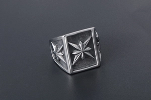 Macro detail of silver titanium steel ring featuring an embossed compass star pattern