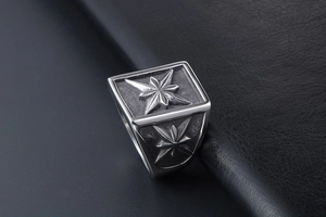 Macro detail of men's stainless steel signet ring with compass star design and black accents