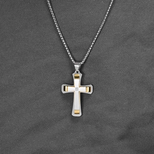Collier croix bicolore en acier inoxydable avec pierre sur fond en tissu gris
