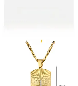 Macro detail of gold titanium steel pendant showing sunburst texture and zircon cross