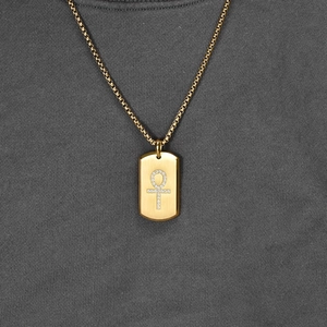 Golden Ankh symbol necklace with square box chain on a dark grey knitted sweater