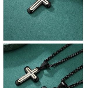 Close-up of black cross necklace with gold inlay and matching metal box chain