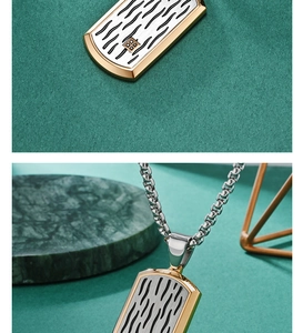 Detail of gold-framed military dog tag pendant with silver wave pattern and box chain