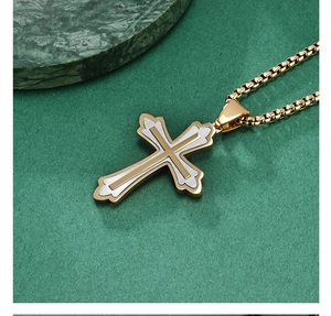 Détail du pendentif croix bicolore en acier inoxydable avec une chaîne dorée élégante