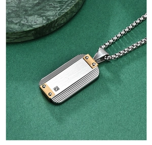 Detail of silver brushed stainless steel dog tag pendant with gold accents and zircon