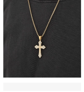 Détail d'un pendentif croix bicolore or et argent sur une chaîne box portée sur un t-shirt