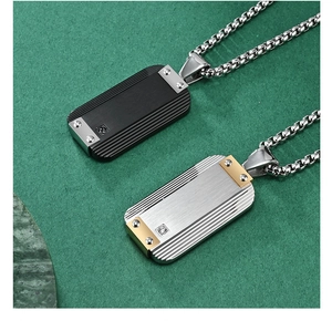Macro view of brushed stainless steel dog tag pendants with rivets and gemstone details