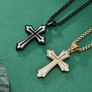 Pendentifs croix classiques en acier inoxydable noir et or sur fond texturé vert émeraude