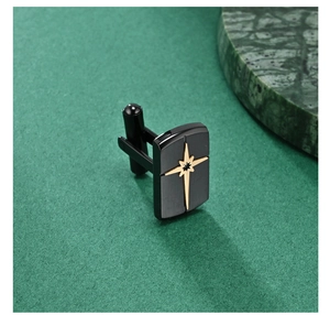 Macro detail of matte black cufflink featuring a golden star emblem on a dark textured base