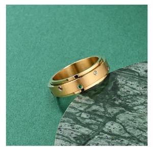 Detail van een gouden draaiende ring met geborstelde textuur en gekleurde zirkonia