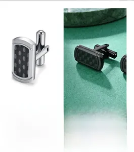 Macro shot of silver cufflinks with black carbon fiber texture and brushed metal finish