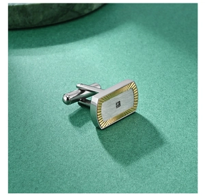 Close-up of silver and gold business cufflinks with fan texture and square crystal