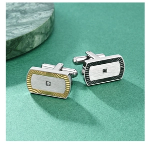 Macro shot of silver brushed metal cufflinks with sunburst texture and square zircon