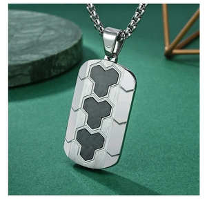 Detail of a rectangular pendant with black carbon fiber inlay and brushed steel texture