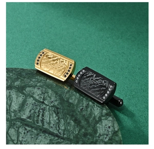 Detailed macro view of gold and black cufflinks with embossed landscape and side diamonds