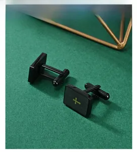 Detail of rectangular black and gold cross cufflinks for men on a dark green surface