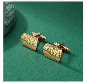 Detailaufnahme goldener Manschettenknöpfe mit Krokostruktur, Silberakzent und Zirkonstein