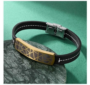 Detail of black leather bracelet with gold geometric plate and steel clasp on marble